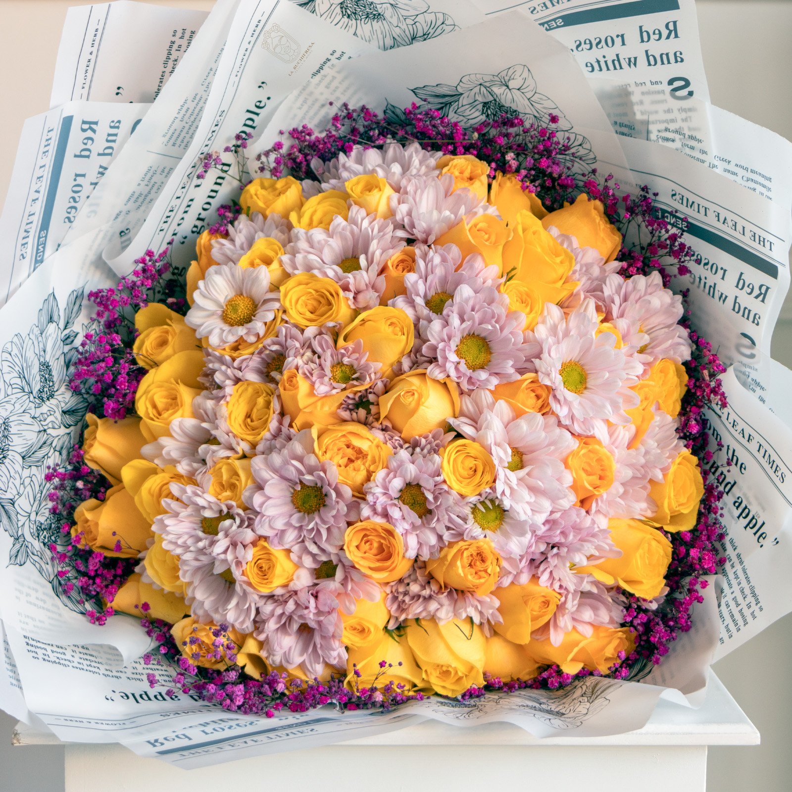 Ramo de 50 rosas amarillas con crisantemo rosa y gypso fucsia alrededor envuelto en papel coreano y liston