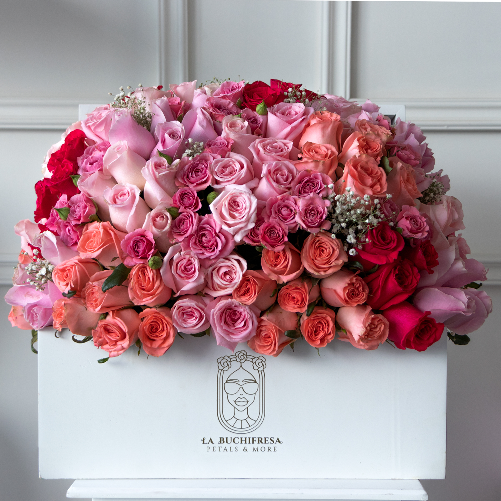 Arreglo con 170 rosas rositas y gypsofilia sobre small white chest