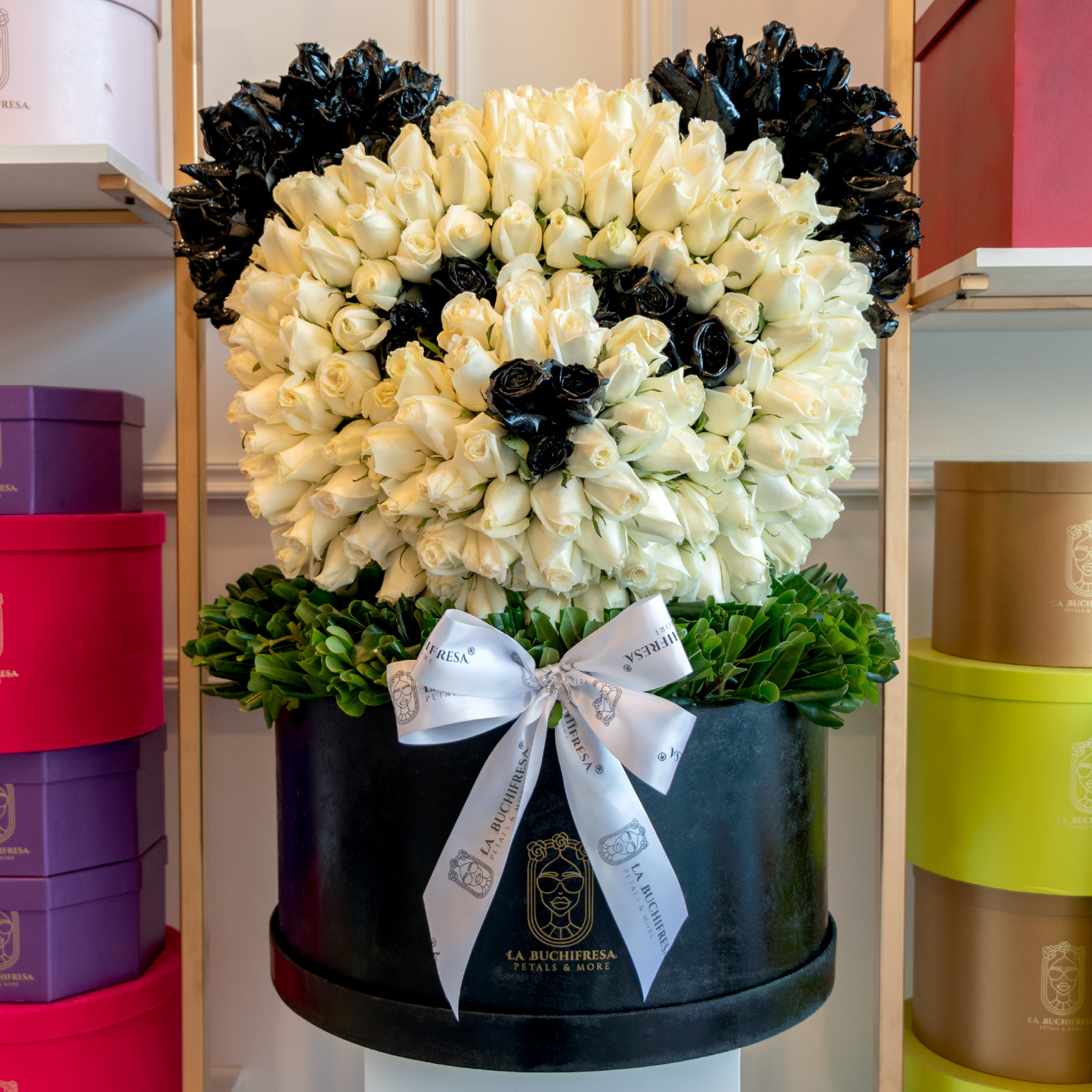 Escultura en forma de cabeza de panda con 550 rosas blancas premium y rosas pintadas de negro con clavo japones sobre medium circular black box con moño