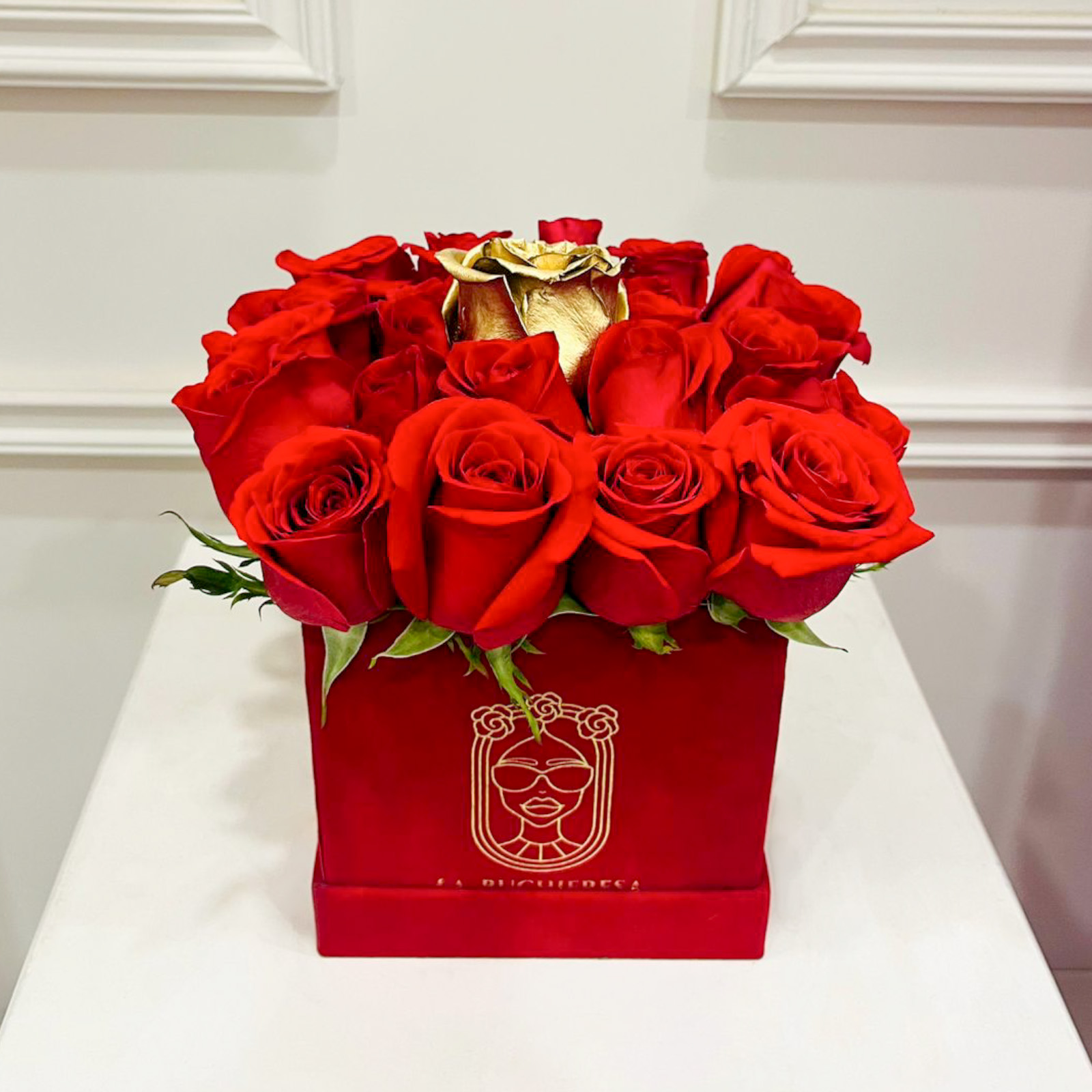 Arreglo de 23 rosas rojas premium al ras y una golden rose elevada en el centro sobre una red velvet mini square box