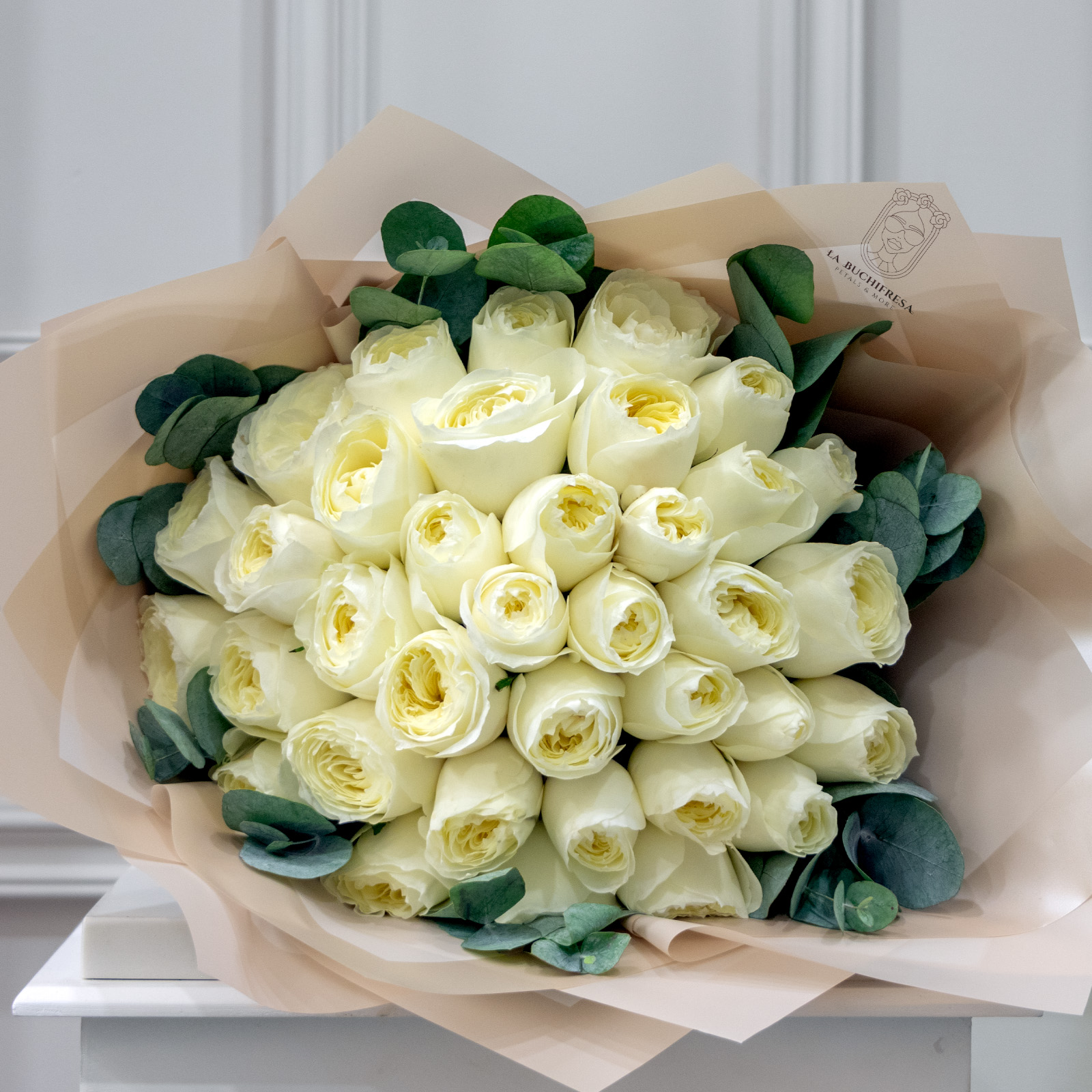 Ramo de 35 rosas inglesas blancas con mini dolar envuelto en papel coreano y liston