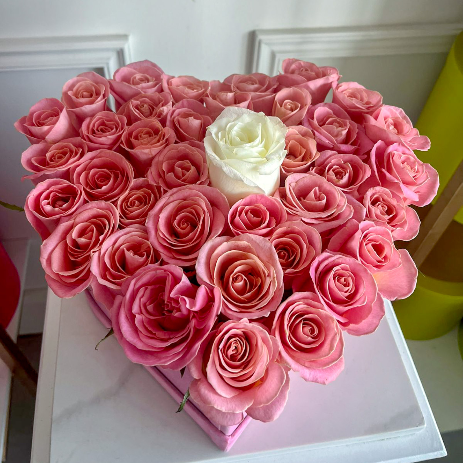 Arreglo de 40 rosas rositas y una rosa blanca premium encima en base de corazon rosa con terciopelo