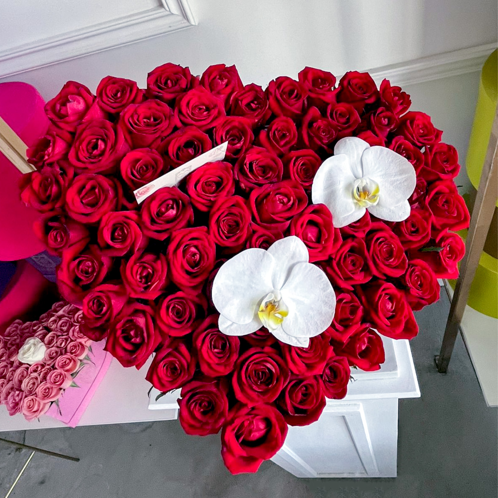 Arreglo de 75 rosas rojas premium con 2 orquideas phalaenopsis en base de corazon negra