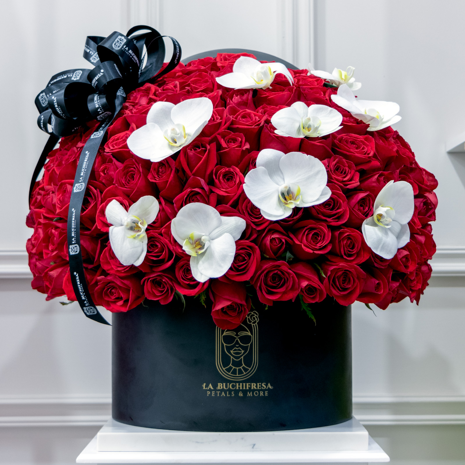 Arreglo en forma de esfera de 300 rosas rojas premium con 9 orquideas phalaenopsis blancas y un moño sobre small circular black box