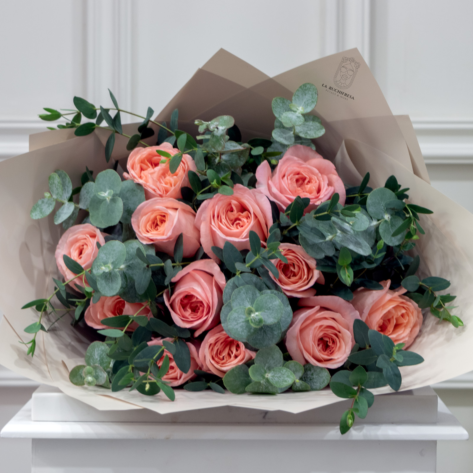 Ramo de 12 rosas inglesas rositas con mini dolar y guni envuelto en papel coreano y liston