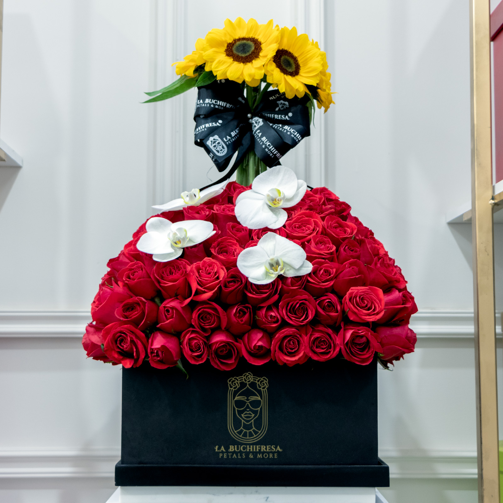 Arreglo en forma de volcan de 250 rosas rojas premium con 8 girasoles y 4 orquideas phalaenopsis sobre square box black