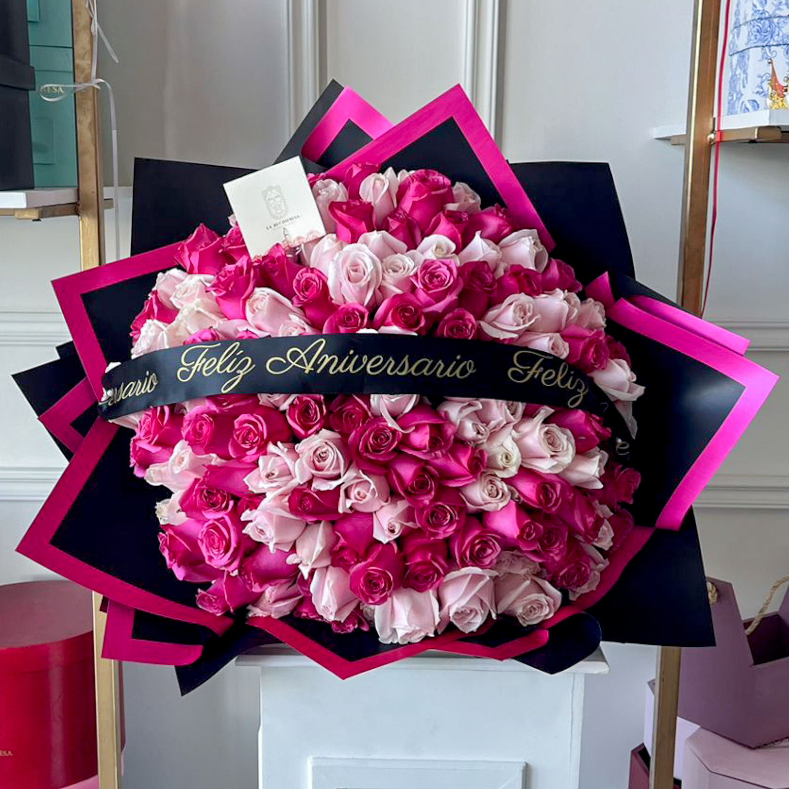 Ramo de 150 rosas rositas y fucsia premium con un liston de feliz aniversario envuelto en papel coreano y liston