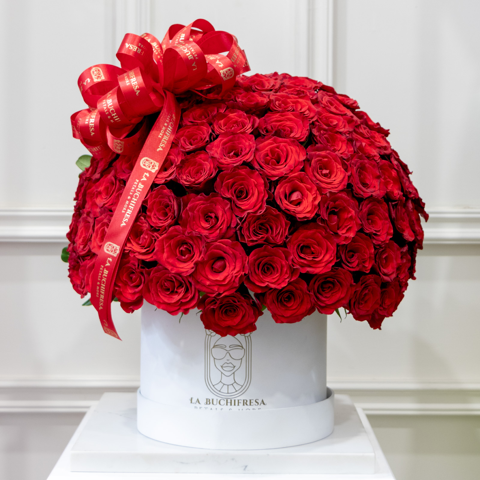 Arreglo de 100 rosas rojas premium en forma de media esfera con clavo japones atras encima de base de madera circular blanca