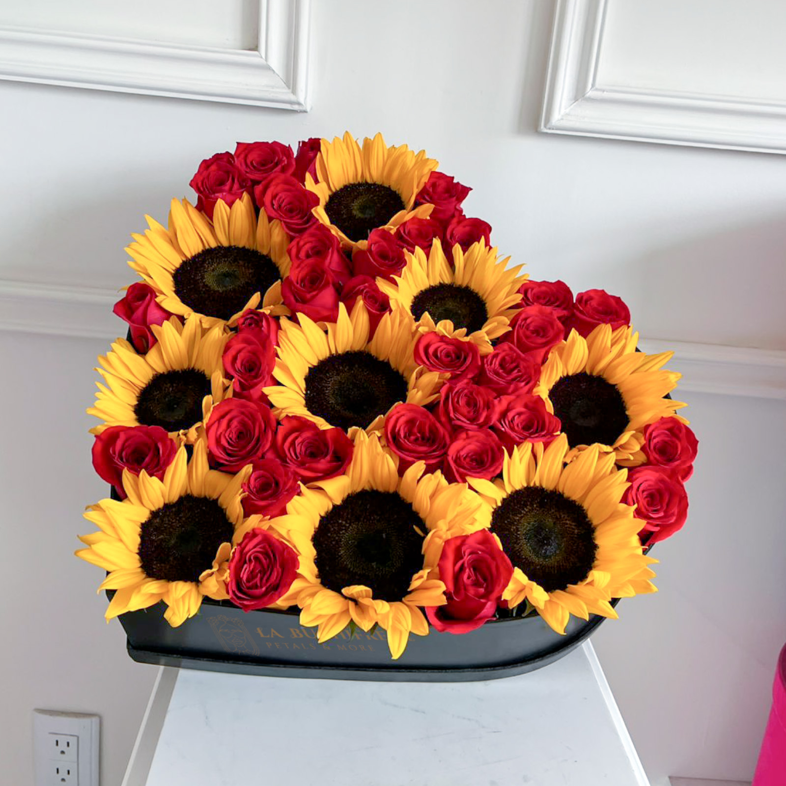 Arreglo en forma de corazon con 35 rosas rojas premium y 9 girasoles en caja de corazon mediana negra