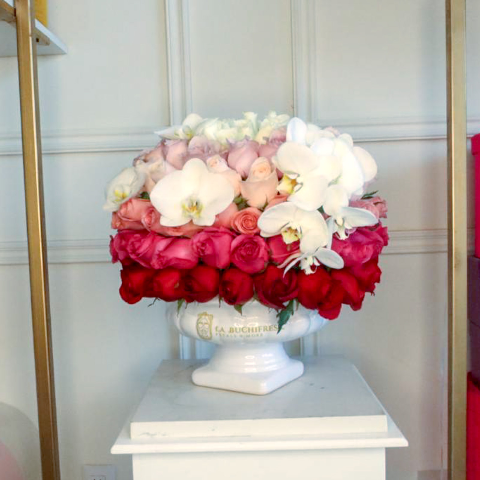 Arreglo de 100 rosas de colores arcoiris premium con orquideas phalaenopsis sobre copa de ceramica blanca