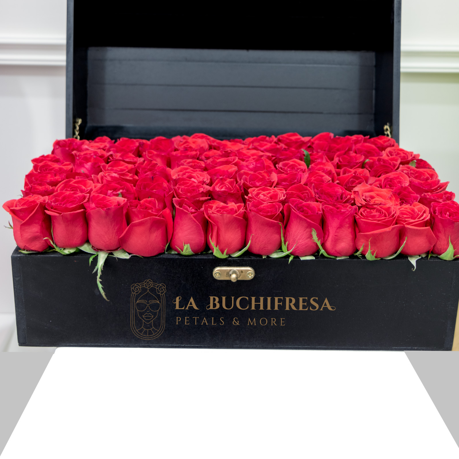 Arreglo de 100 rosas rojas premium sobre cofre de madera negro