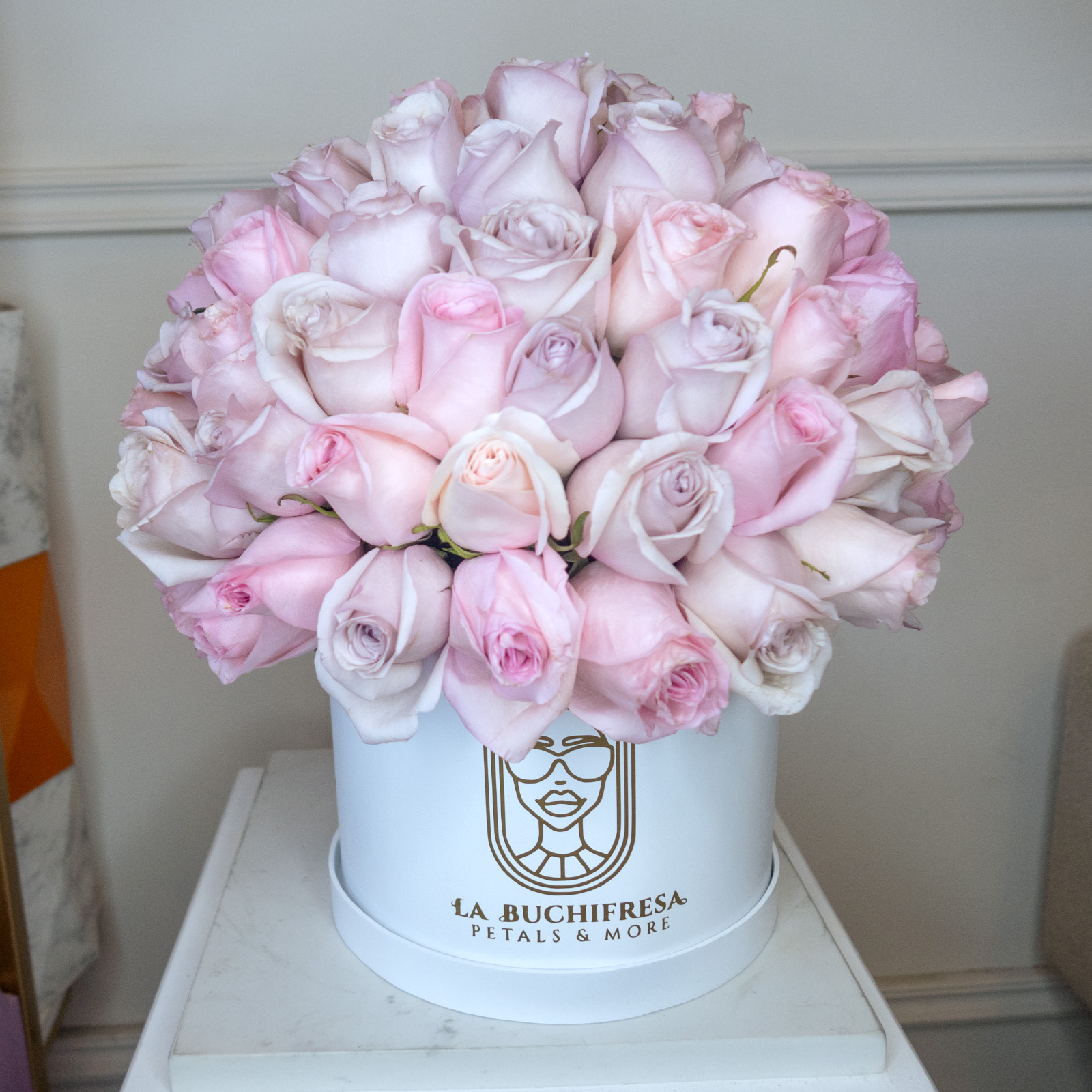Arreglo de 100 rosas rositas y lilas premiun en forma de esfera sobre base de madera circular blanca mediana