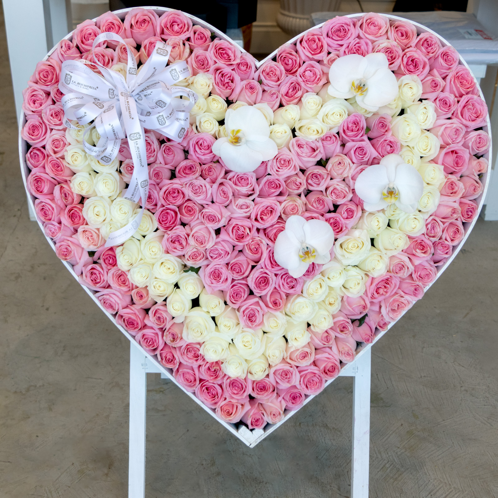 Arreglo de 300 rosas rositas y blancas premium con orquideas phalaenopsis en base de corazon stand-up blanca