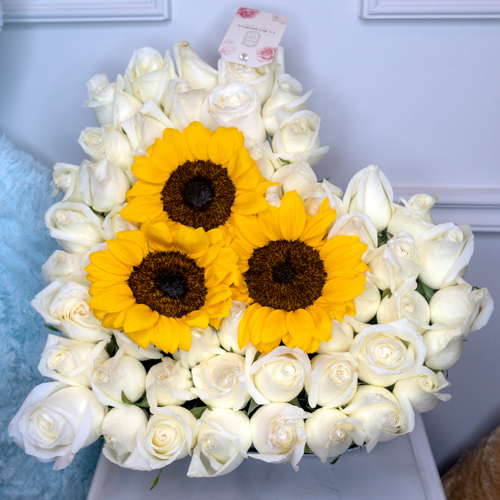 Arreglo de 50 rosas blancas premium y 3 girasoles en caja de corazon negra mediana