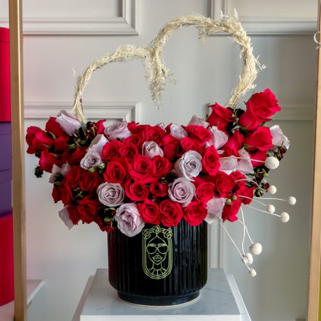 Arreglo de 75 rosas lila y fucsia premium con un corazon blanco arriba de caspia pintada con toques de baby rose roja
