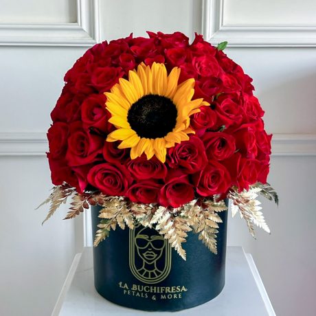 Arreglo de 75 rosas rojas premium en forma de media esfera con un girasol en medio y dolar pintado de dorado alrededor sobre base de madera negra circular